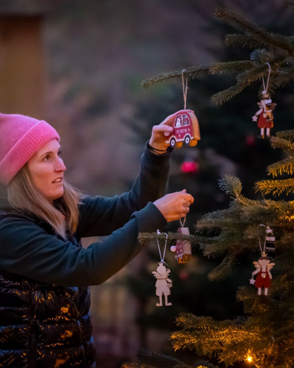 Ein Christbaum wird im Freien mit kleinen Figuren geschmückt