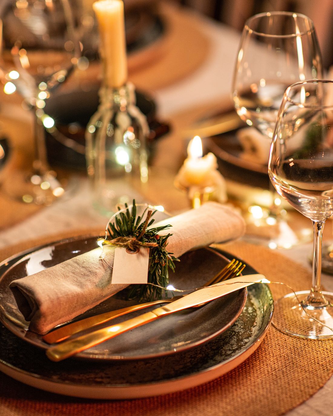 Festlich gedeckter Tisch mit Kerzen, Tannenzweig und goldenem Besteck
