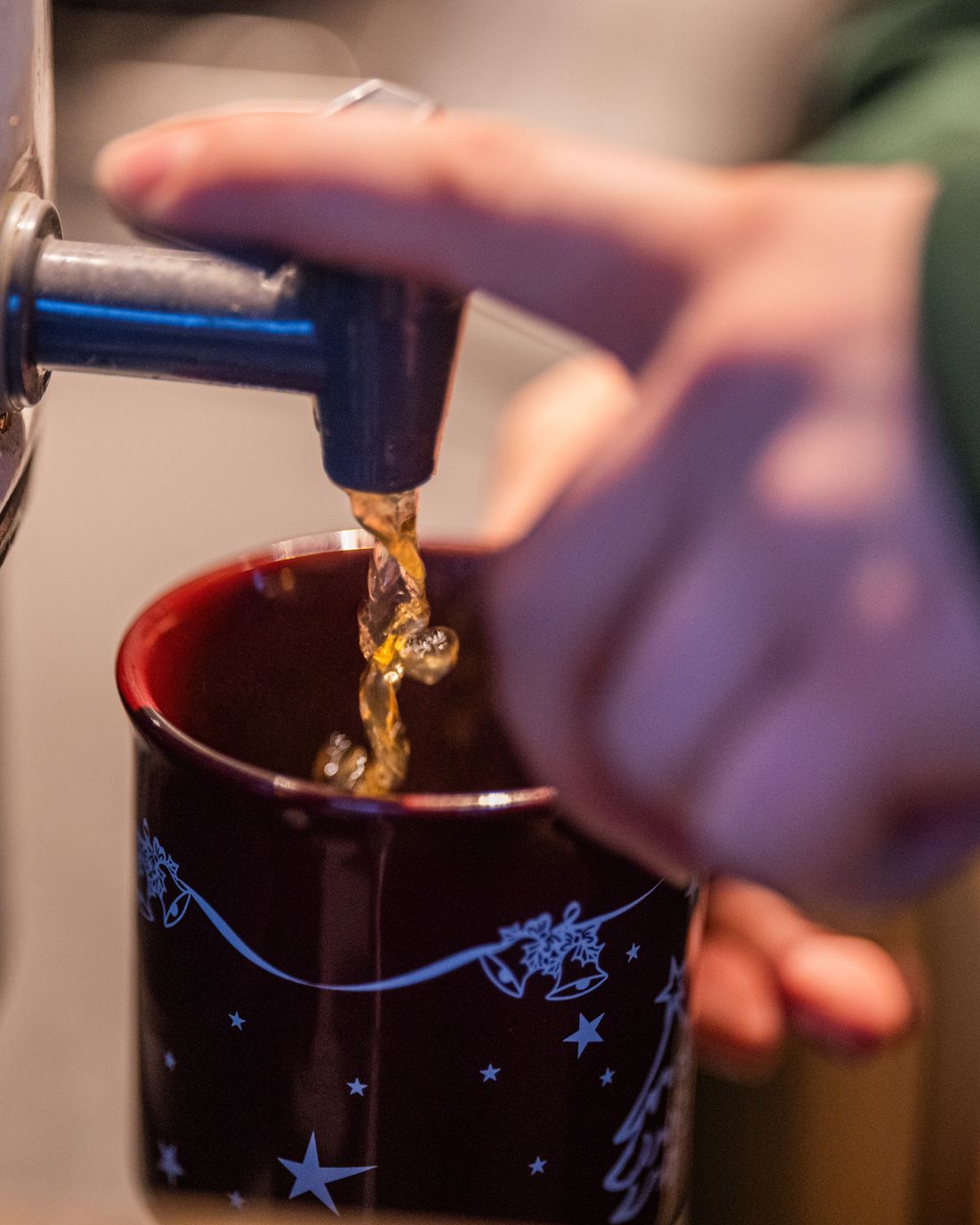 Glühwein wird aus dem Kessel in einen Becher gefüllt